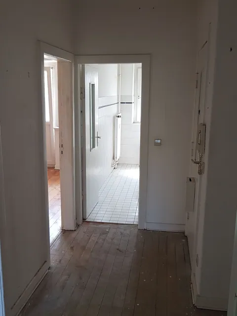 Leerer Wohnungsflur nach der Räumung mit Blick durch offene Türen in die anschließenden Räume